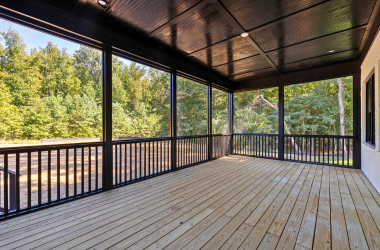 Residential wood deck with railing and seating space.
